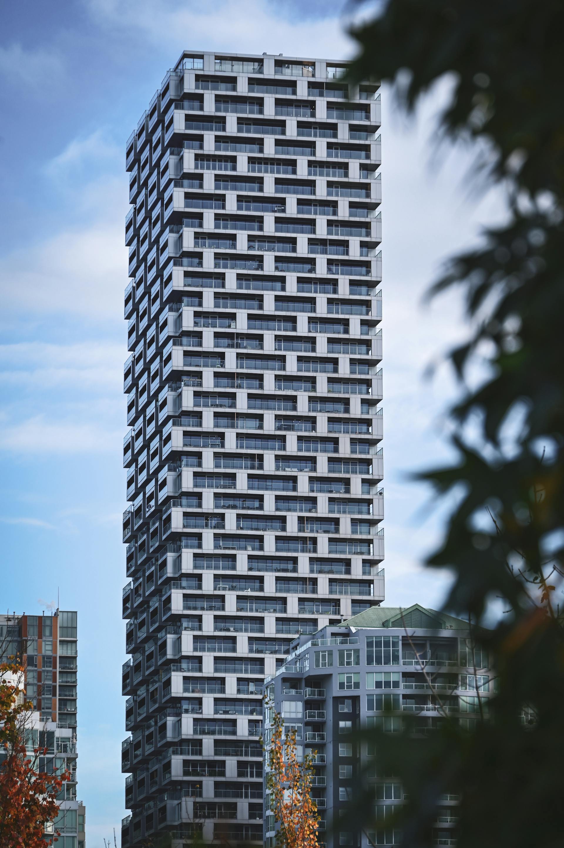 A modern concrete-and-glass residential tower rises above the West End of Vancouver, BC